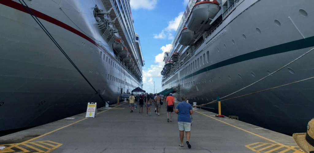 people walking along the pathway between two large cruise ships
