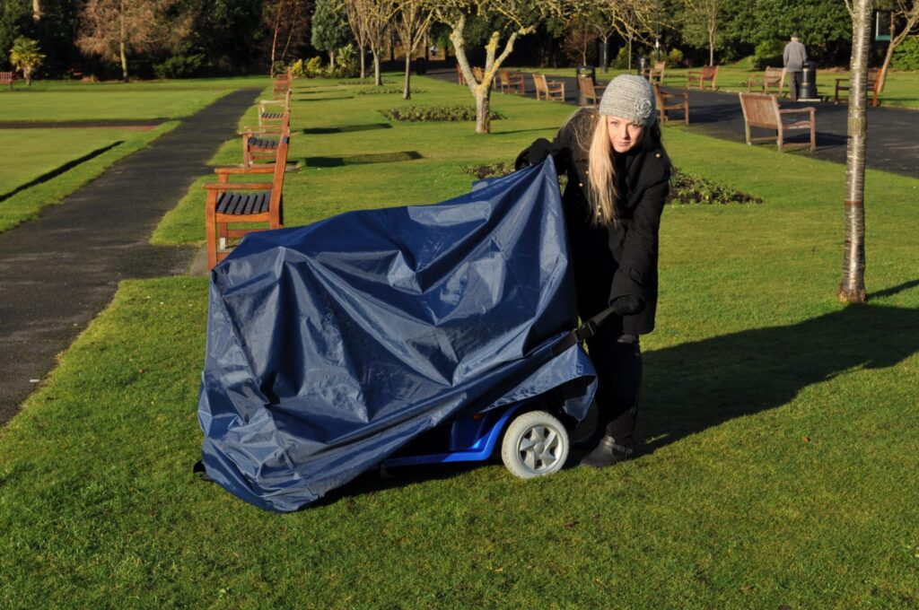 lady putting a rain cover on a mobility scooter