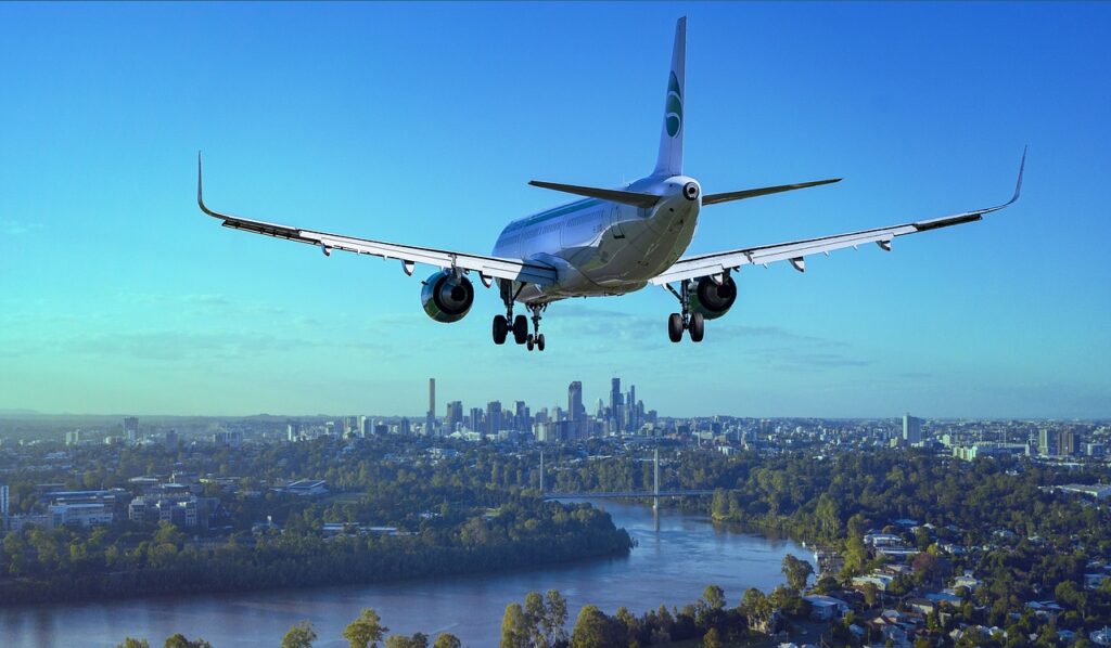 plane flying over a river and city in the background