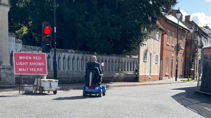 Man on mobility scooter running a red light on the road