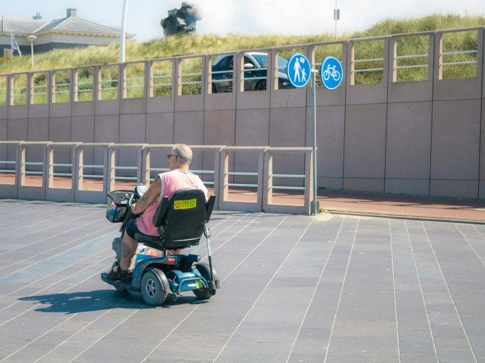 an elderly man riding a mobility scooter in an urban area