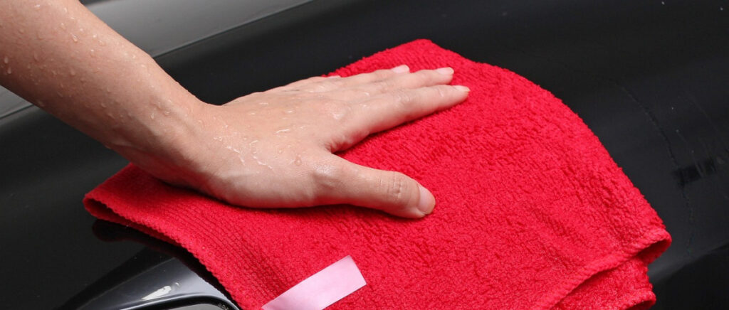 A person cleaning a surface with a red microfibre cloth