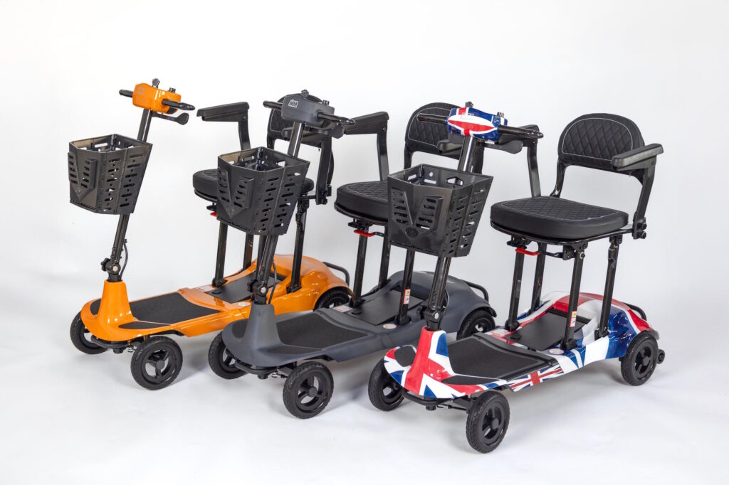 three mobility scooters lined up - one in orange, one in grey and one with a union jack pattern