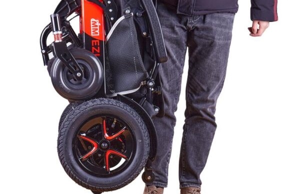 Bottom half of a man showing him carrying a folded up Ezi Fold Pro powerchair